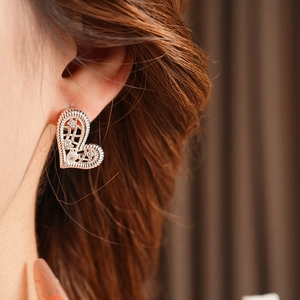 Close-up of rose gold filigree heart earring with cubic zirconia on female ear