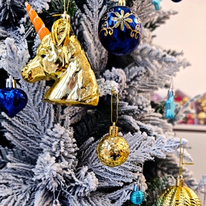 Gros plan d'une licorne dorée et de boules bleues sur une branche de sapin de Noël enneigée