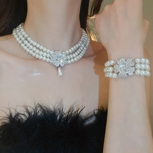 Macro view of triple-strand pearl necklace and bracelet set with crystal flower charms