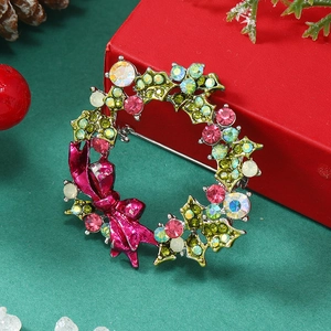 Macro view of Christmas wreath brooch with green holly leaves, rhinestones and pink bow