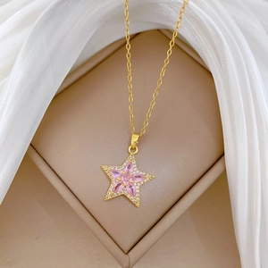 Gros plan du collier en or avec pendentif étoile rose et diamants sur soie