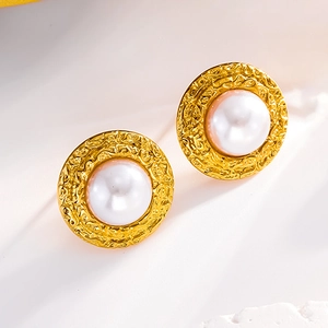 Detailed macro view of vintage gold stud earrings with white pearl and hammered texture