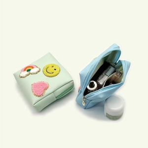 Detailed internal view of travel makeup bags with rainbow and smiley chenille patches