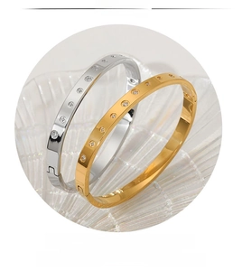 Detailed close-up of gold and silver stainless steel bangles with zircon inlay on glass tray