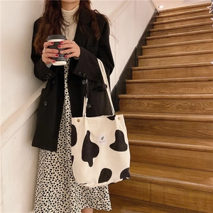 Primer plano del bolso tote de lona con estampado de vaca en una escalera de madera retro