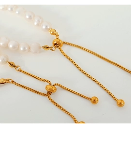 Macro shot of natural freshwater pearls and adjustable golden slider clasp detail