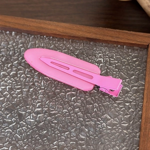 Primo piano di un fermaglio per capelli rosa opaco color caramella su vetro texture