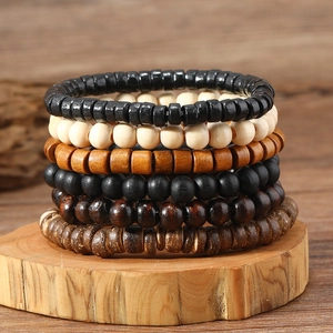 Macro shot of 6-piece stacked handmade wooden bead bracelets on a rustic wood slice