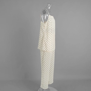 Detailed view of white polka dot camisole and wide-leg trousers in silky fabric