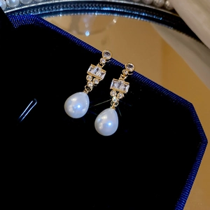 Detail of 18k gold plated earrings featuring sparkling zircons and a teardrop pearl