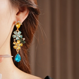 Close-up of vintage flower tassel earring with blue and yellow crystals on model ear
