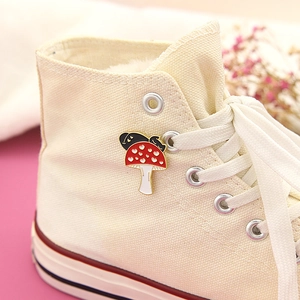 Enamel pin featuring a black cat hiding on a red mushroom on a canvas sneaker