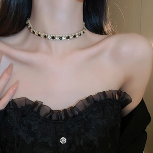 Gros plan d'un collier choker doré avec pierres noires carrées et cristaux sur un mannequin