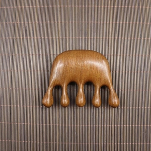 Macro detail of natural sandalwood massage comb with five polished rounded points