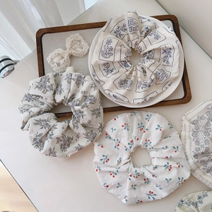 Detailed close-up of floral print cotton scrunchies set in rustic decorative trays