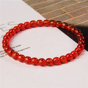 Macro shot of 6mm red agate beads with gold Buddhist mantra engravings on elastic bracelet
