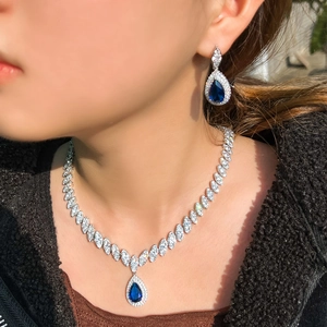 Elegant bridal jewelry set with blue pear-cut zircons and white crystals on a model