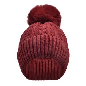 Detail of cable knit pattern and large faux fur pompom on burgundy winter beanie hat