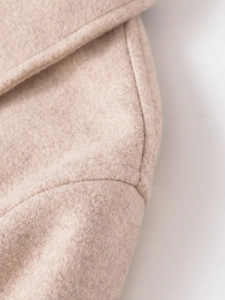 Close-up of beige wool fabric texture showing high-quality stitching on jacket collar