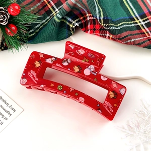 Macro detail of red Christmas hair claw clip with snowman and bell prints on festive tray