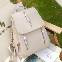 Outdoor shot of beige nylon backpack with purple handles on a folding chair
