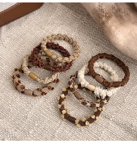 Close-up of 6-piece woven hair ties in autumn brown tones with decorative beads