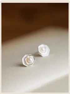 Detailed view of silver lotus leaf earrings with pearl center and radial texture