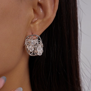 Détail de boucle d'oreille carrée argentée avec chaîne irrégulière et perles