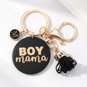 Detail of DIY keychain with gold Boy Mama charms and black leather tassel pendant