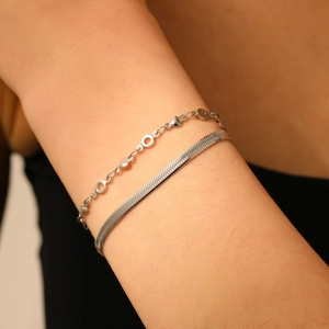 Détail du bracelet double couche argenté avec breloques cœur et chaîne serpent plate au poignet