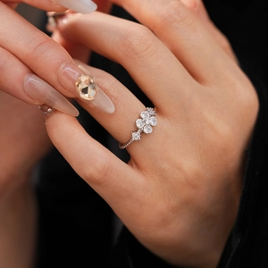 Detailed view of silver flower ring with zircons worn by a model in a 45-degree angle shot