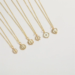 Close-up of 14K gold plated necklaces featuring white enamel charms and zircon pendants