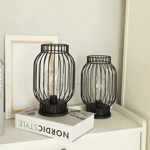 Modern black metal frame decorative lanterns with LED copper wire bulbs on a white shelf