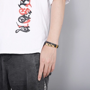 Detail of men's double-layer black leather bracelet with golden infinity charm on wrist