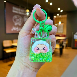 Detailed close-up of a green liquid sand keychain with a cute white cartoon mascot