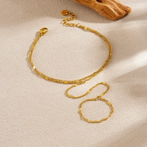 18k gold plated stainless steel hand chain with round sequins on a textured beige surface