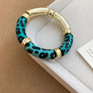 Gros plan d'un bracelet géométrique en acrylique avec maillons dorés et résine léopard bleue