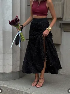 Detail of high-waist black long skirt with 3D floral applique and side high slit design