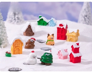 Close-up of miniature Christmas resin village pieces featuring snowy houses and reindeer