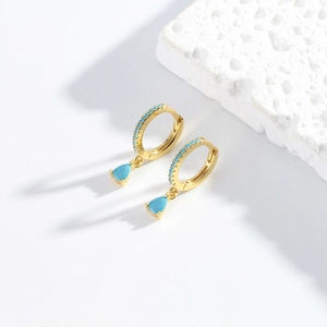 Macro detail of S925 sterling silver gold earrings with teardrop turquoise pendant