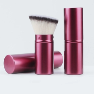 Macro detail of portable telescopic makeup brush showing retractable pink metal case and soft bristles