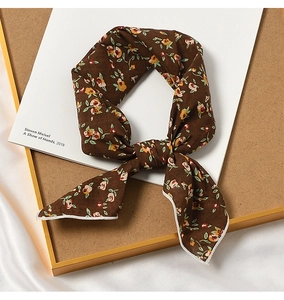 Close-up of brown floral cotton linen neck scarf on a wooden tray with elegant lighting