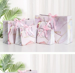 Detail of pink marble gift bags with golden accents, silk ribbons and Happy Times text