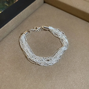 Detailed close-up of multilayer silver beaded chain bracelet with adjustable lobster clasp