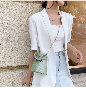 Detail of green crocodile pattern bucket bag with elegant gold chain shoulder strap