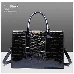 Close-up of black crocodile pattern leather handbag with gold metal logo and round handles
