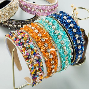 Detailed close-up of Baroque style wide headbands with colorful rhinestones on a metal stand