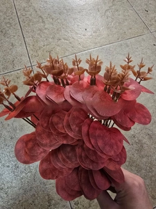 Gros plan de tiges d'eucalyptus artificielles rouge foncé avec des feuilles ovales