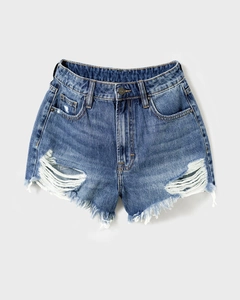 Close-up of distressed denim shorts detailing ripped holes and frayed fringe hem