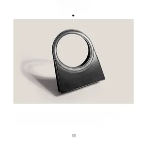 Close-up of matte black minimalist geometric handbag with circular handle and fine stitching